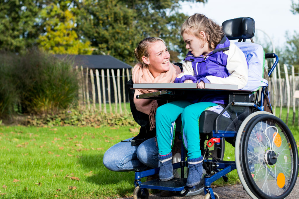 Young girl in a wheelchair with adult support