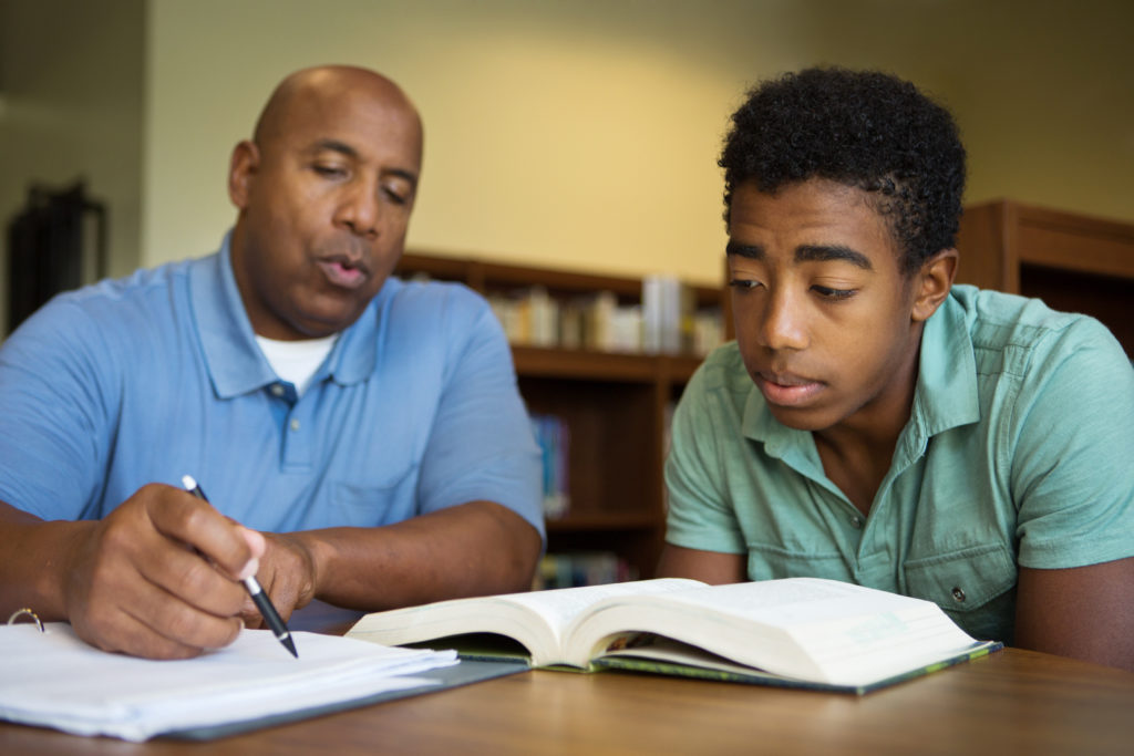 Adult male helping young adult with paperwork