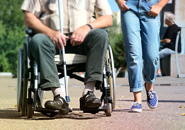 Man in wheelchair with person walking beside him