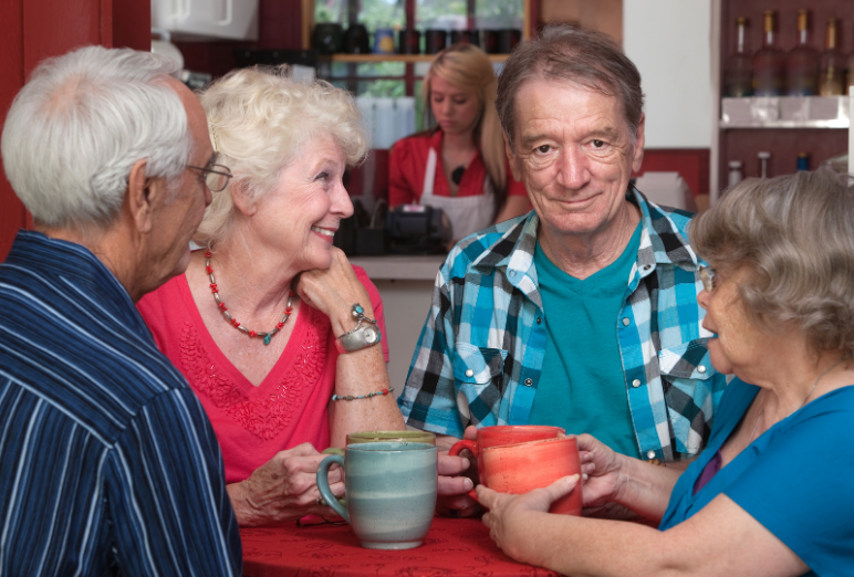 A group of older adults chatting and drinking coffee