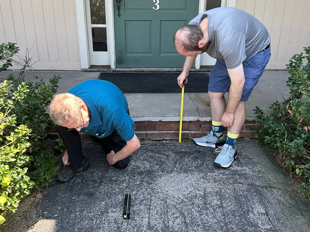 Jim Lyons and Brandon measuring the approach and step at a building entrance.